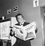Tony Martin reading Newspaper in front of soda machine