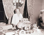 Perle Mesta standing at a table in front of decorations