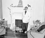 Louis Prima standing in front of a fireplace