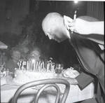 Dwight 'Ike' Eisenhower leans over to blow out the candles on his birthday cake