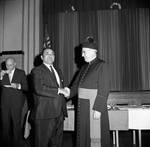 Msgr. Dooley shakes hands at an event for St. Francis Xavier, Newark, NJ by Ace (Armando) Alagna, 1925-2000