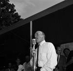 A man standing at the microphone entertains the crowd at a picnic event for Essex County Sheriff Ralph D'Ambola by Ace (Armando) Alagna, 1925-2000